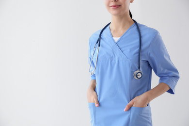 Closeup view of young doctor with stethoscope on light background