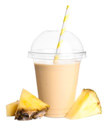 Plastic cup of tasty pineapple smoothie and fresh fruit on white background