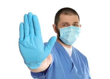 Doctor in protective mask showing stop gesture on white background. Prevent spreading of coronavirus