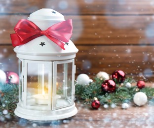 Image of Christmas lantern with burning candle and festive decor on wooden table