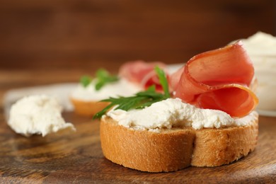 Photo of Delicious sandwich with cream cheese, jamon and parsley on wooden board, closeup