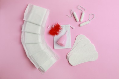 Menstrual pads and other feminine hygiene products on pink background, flat lay
