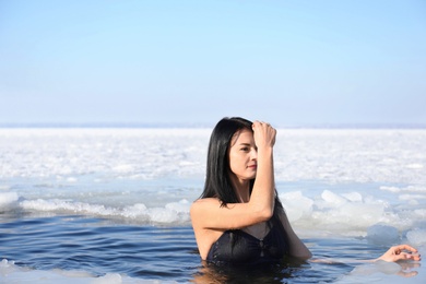 Woman immersing in icy water on winter day. Baptism ritual