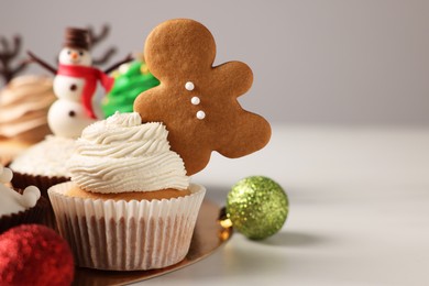 Tasty Christmas cupcake with gingerbread man and baubles on white table. Space for text