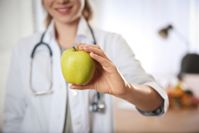 Nutritionist with fresh apple in her office, closeup