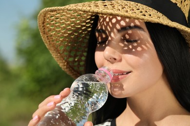 Photo of Beautiful young woman drinking water outdoors, closeup. Refreshing drink