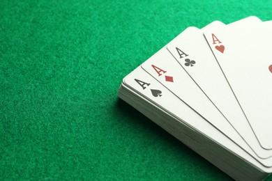 Photo of Four aces playing cards on green table, closeup. Space for text