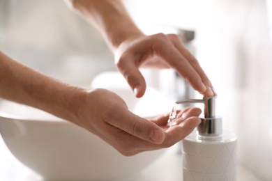 Man using soap dispenser in bathroom, closeup
