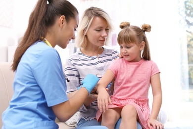 Children's doctor vaccinating little girl at home