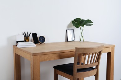 Comfortable workplace with wooden desk near white wall at home