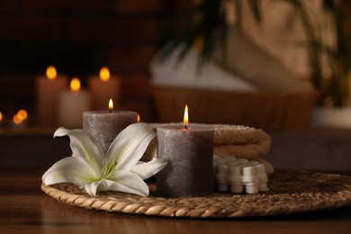 Photo of Spa composition with burning candles, lily flower and towels on wooden table in wellness center