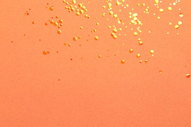 Shiny bright glitter on coral background, flat lay. Space for text