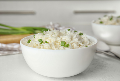 Bowl with tasty cooked rice on white table