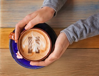 Coffee Break. Woman with cup of cappuccino at wooden table, top view