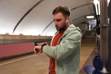 Young man with earphones waiting for train at subway station. Public transport