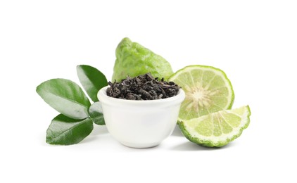Dry bergamot tea leaves in bowl and fresh fruits on white background