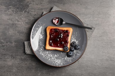 Delicious toast served with jam and blueberries on grey wooden table, top view