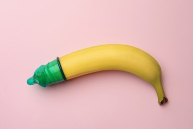 Banana with condom on pink background, top view. Safe sex concept