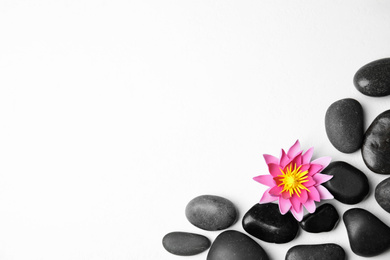 Stones with lotus flower and space for text on white background, flat lay. Zen lifestyle