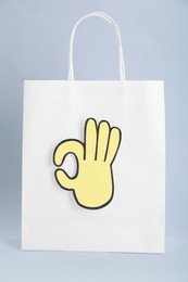 Photo of Paper bag and cutout of okay hand gesture on light grey background