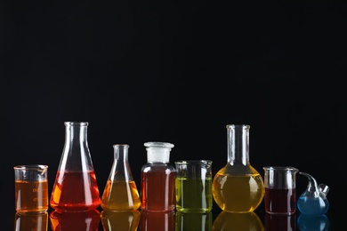 Laboratory glassware with colorful liquids on black background