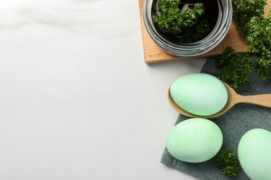 Photo of Turquoise Easter eggs painted with natural dye and curly parsley on white table, flat lay. Space for text