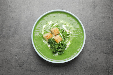 Tasty kale soup with croutons on grey table, top view
