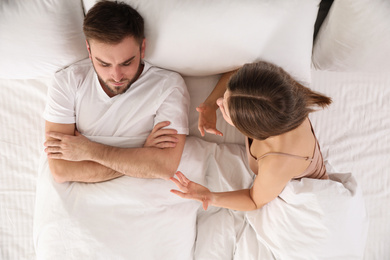 Young couple quarreling in bed at home, top view. Relationship problems