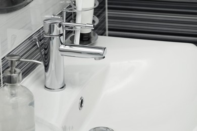 Clean white sink with shiny water tap in bathroom