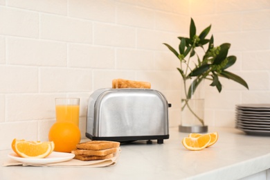 Modern toaster and tasty breakfast on counter in kitchen