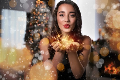 Beautiful young woman wearing elegant dress blowing kiss in room decorated for Christmas