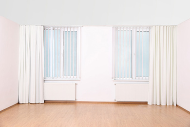 Windows with elegant curtains and blinds in empty room