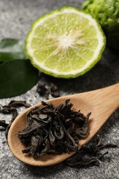 Dry bergamot tea leaves and fresh fruit on grey table, closeup