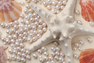 Beautiful sea shells, starfish and pearls on beige background, flat lay