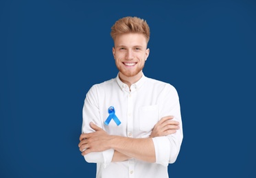 Photo of Young man with ribbon on blue background. Urology cancer awareness