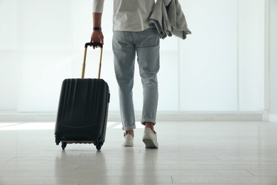 Man with black travel suitcase in airport