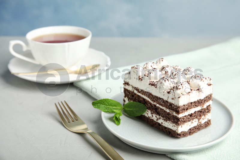 Delicious tiramisu cake with cup on table, space for text