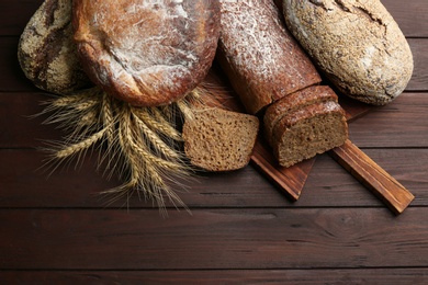 Different kinds of fresh bread on wooden table, flat lay