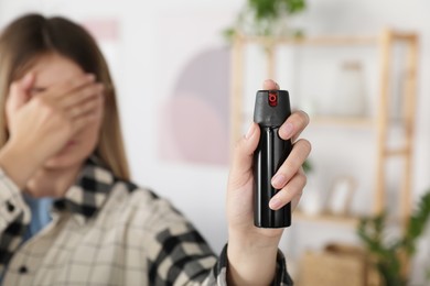 Woman using pepper spray indoors, focus on hand
