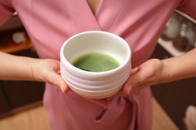 Photo of Master offering cup of freshly brewed matcha tea during traditional ceremony, closeup