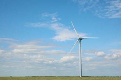 Photo of Beautiful view of field with wind turbine. Alternative energy source