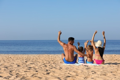 Family on sandy beach near sea. Summer holidays