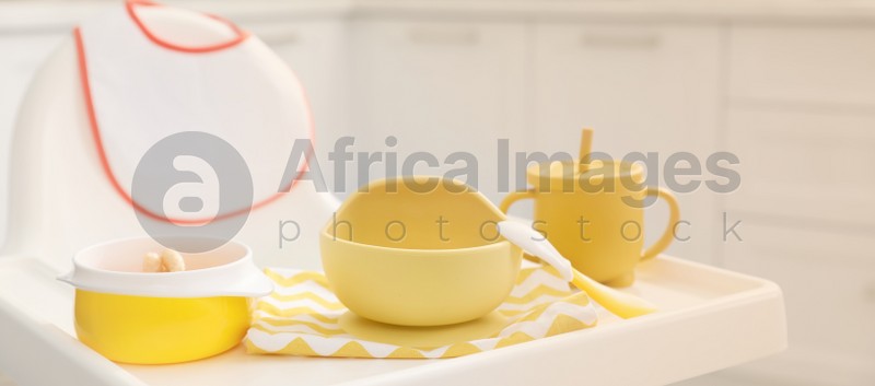 High chair with set of baby tableware on tray indoors, closeup view. Banner design