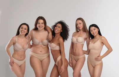 Group of women with different body types in underwear on light background