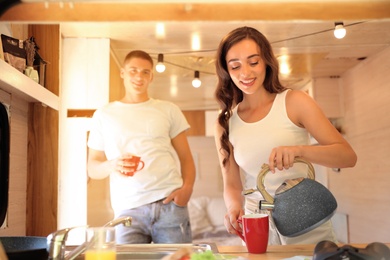Happy young couple having breakfast in trailer. Camping vacation