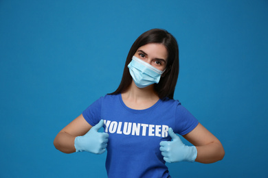 Female volunteer in mask and gloves on blue background. Protective measures during coronavirus quarantine