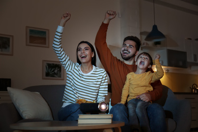 Emotional family watching TV using video projector at home
