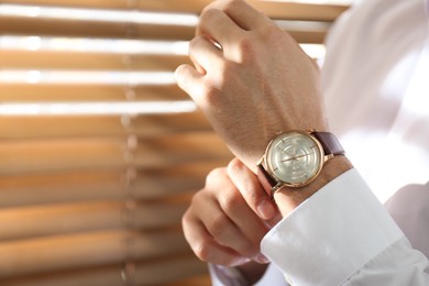 Man with luxury wrist watch on blurred background, closeup. Space for text