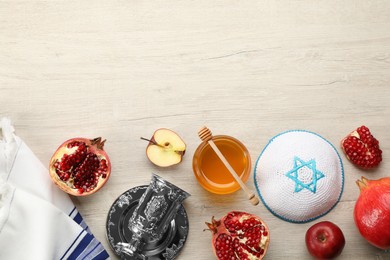 Flat lay composition with Rosh Hashanah holiday attributes on white wooden table. Space for text