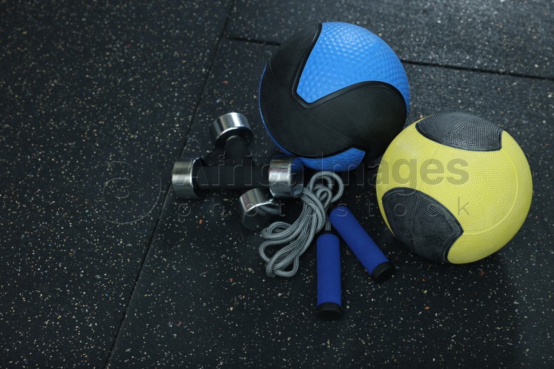 Medicine balls, dumbbells and skipping rope on floor, space for text
